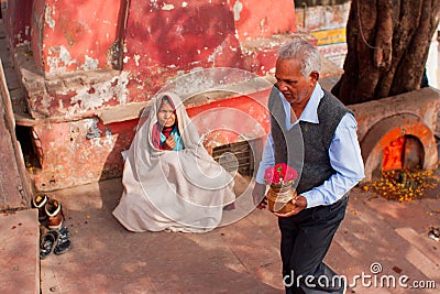 Elderly man with donations going to the temple by poor woman