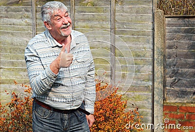 Elderly man smiling and giving thumbs up sign.