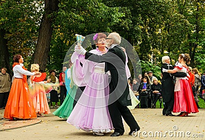 Elderly steams in ball suits dance on city square