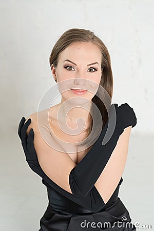 Elegance woman in black gloves and dress on light. Portrait, cross hands