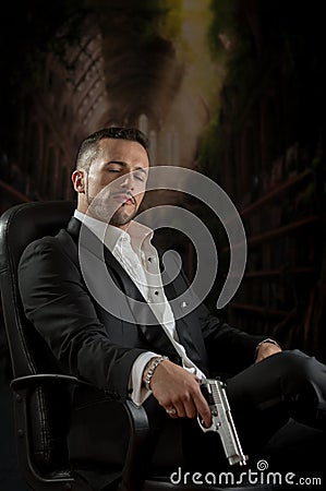 Elegant man sitting in a chair holding gun over