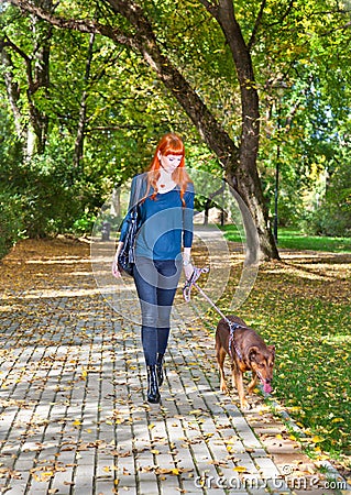 Elegant woman walking her big dog in the park