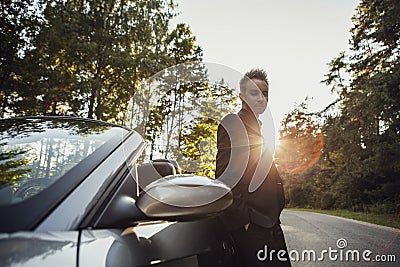 Elegant young happy man in convertible car outdoor.