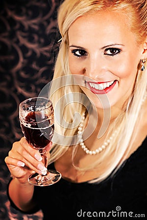 Elegantly dressed light hair model holding a crystal glass
