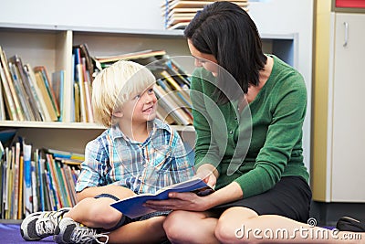 Elementary Pupil Reading With Teacher In Classroom