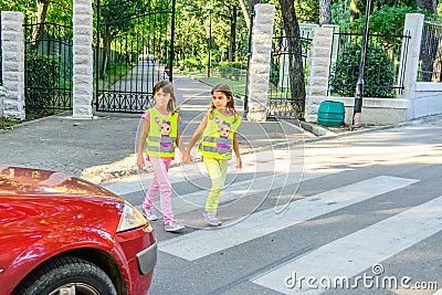 Elementary school kids crossing the street wearing a vest with the stop sine on it