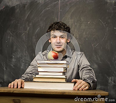 Emotional student with the books and red apple in class room, at blackboard