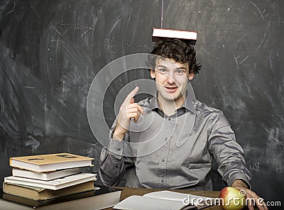Emotional student with the books and red apple in class room, at blackboard