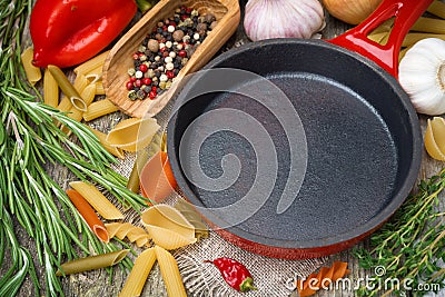 Empty frying pan, vegetables and spices on wooden background