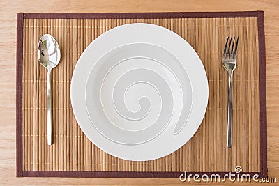 Empty plate spoon and fork on mat