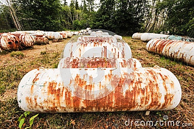 Empty propane storage tanks litter a field