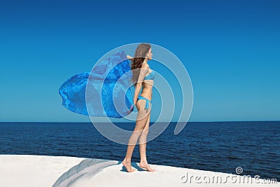 Enjoyment. Fashion model woman with blowing tissue over blue sky