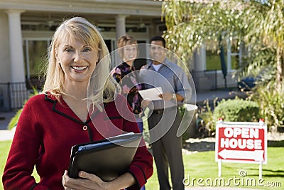 Estate Agent With House And Couple In Background