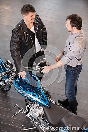 Examining motorcycle. Cheerful young sales executive consulting