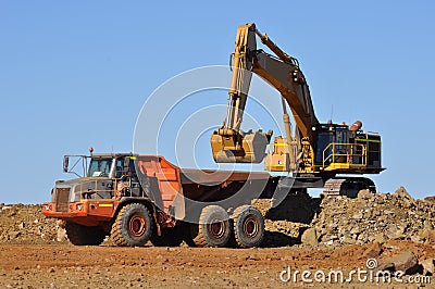 Excavator loading truck in mine quarry
