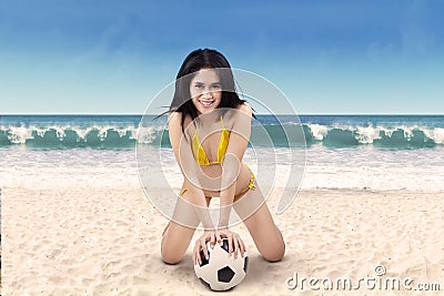 Excited woman in bikini holding soccer ball