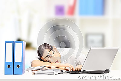 Exhausted businessman sleeping on a desk in his office