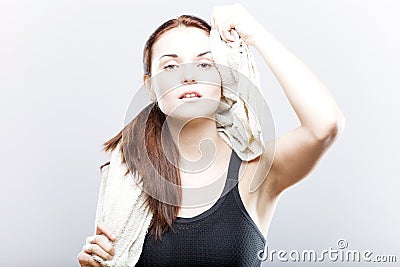 Exhausted woman after training wiping face with towel