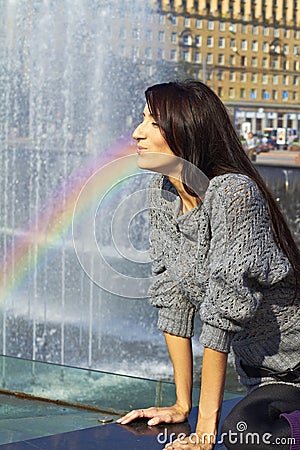 Expressive production figures. girl with bright makeup brunette with long hair in a gray lace sweater Spray Rainbow water fountain