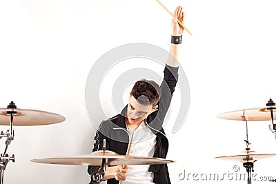 Expressive young drummer playing at the drums with drum stick