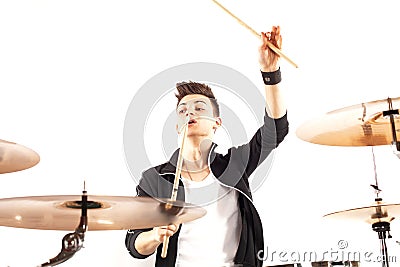 Expressive young drummer playing at the drums with drum stick