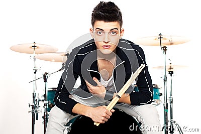 Expressive young drummer playing at the drums with drum stick