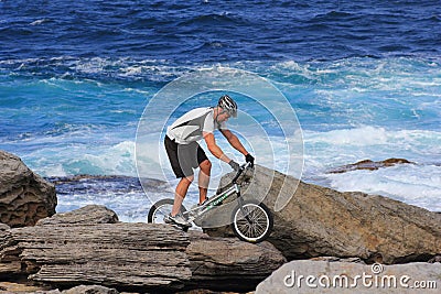 Extreme biking man on rocky shore