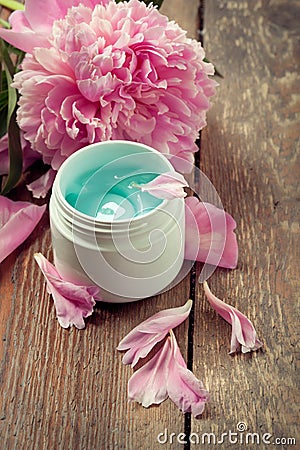 Face organic cream with peonies on an old wooden table