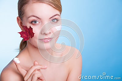 Face of young woman girl with red maple leaf cream