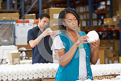 Factory Worker Checking Goods On Production Line