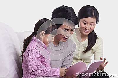 Family bonding together, smiling and reading on the sofa, studio shot