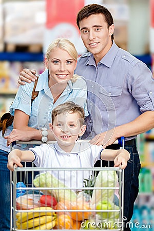 Family drives shopping trolley with food and son sitting there