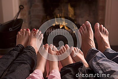Family of feet warming at a fireplace