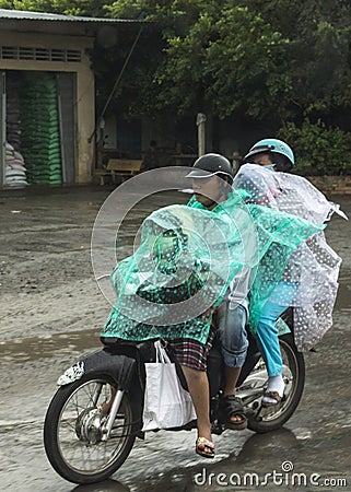 Family of four travel in the rain on motorbike.