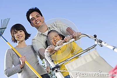 Family With Lawn Mower And Gardening Fork