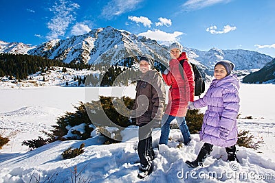 Family (mother with two children) take a walk on winter mountain