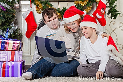Family with notebook near Christmas tree.