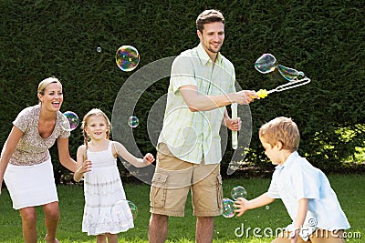 Family Playing With Bubbles In Garden