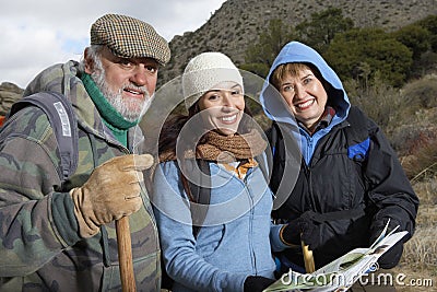 Family With Poles And Map Hiking Together In Desert