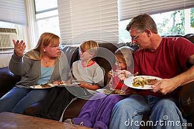 Family With Poor Diet Sit On Sofa Eating Meal And Arguing