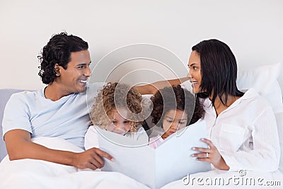 Family reading a story in the bedroom