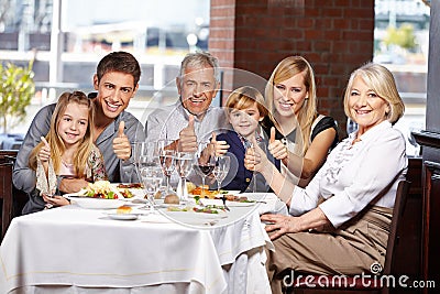 Family in restaurant holding thumbs