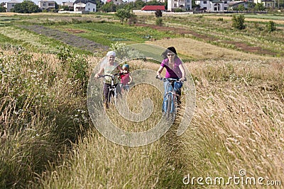 Family riding a bicycles in the meadow