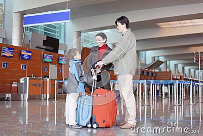 Family standing in airport hall with suitcases