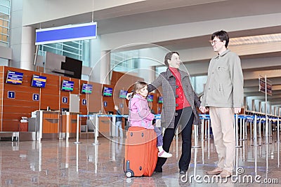 Family with suitcase standing in airport hall