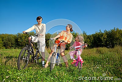 Family from three persons on bicycles in country.