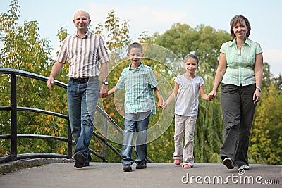 Family with two children is walking on bridge