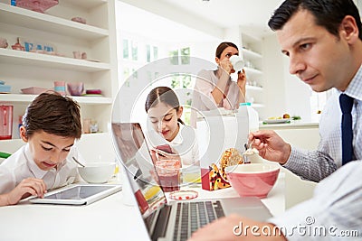 Family Using Digital Devices At Breakfast Table