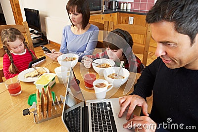 Family Using Gadgets Whilst Eating Breakfast