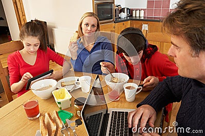 Family Using Gadgets Whilst Eating Breakfast